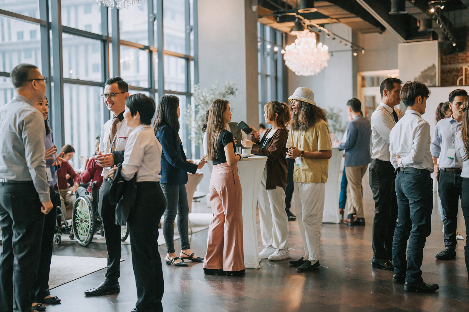 Menschen in formeller Kleidung beim Networking-Event in einem modernen Raum.